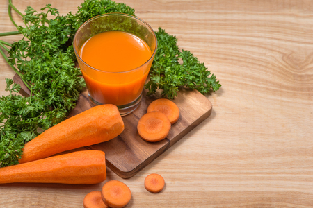 Glass of fresh carrot juice with vegetables on wooden table.の写真素材