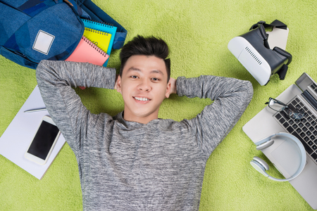 Top view of cheerful handsome man lying on floor with different devicesの写真素材