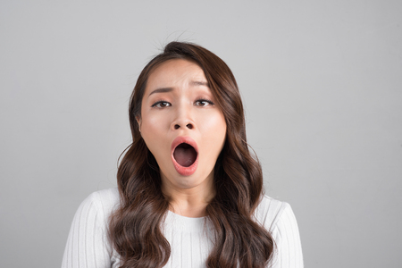 Asian woman yawns, bored, isolated on gray backgroundの写真素材