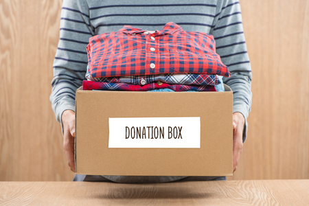 Donation box for poor with clothing in male handsの写真素材
