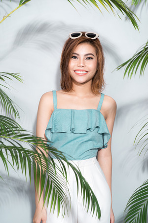 Beauty summer. Beautiful asian woman between palm leaves.の写真素材
