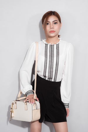 Full-length portrait of beautiful asian woman holding a bag walking over gray background.の写真素材