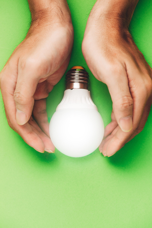 Hands guarding energy saving eco lamp close upの写真素材