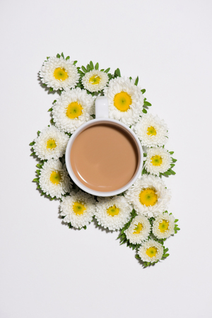 Flat lay of green leaves and flowers pattern with cup of coffee on white backgroundの写真素材