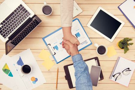 Confident business handshake. Top view of two business people shaking hands at office deskの写真素材