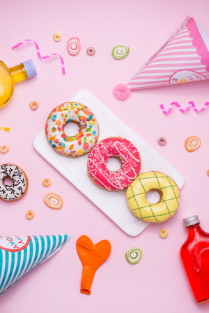 Party. Different colourful sugary round glazed donuts and bottles of drinks on pink background.の写真素材