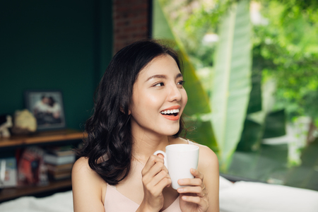 Pretty woman enjoying her morning coffee at homeの写真素材