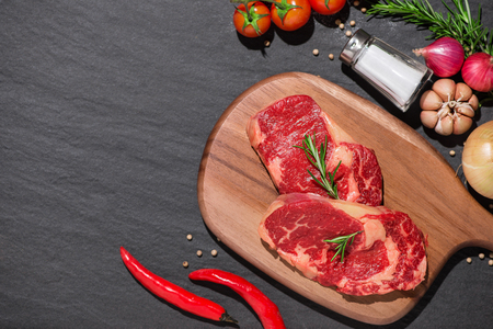 Raw beef on a cutting board  with spices and ingredients for cooking.の写真素材