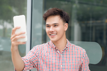 Social media communication. Casual man video call using mobile smart phone outdoorsの写真素材