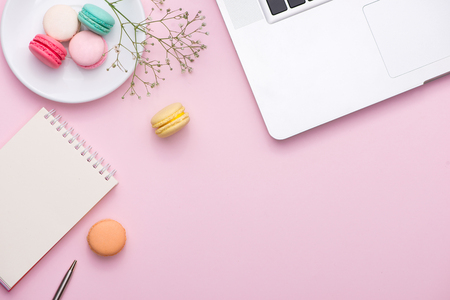 Flatlay of laptop, cake macaron and cup of tea on pink table. Beautiful breakfast with macaroon.の写真素材