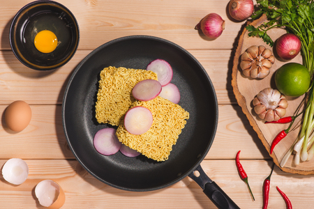 Instant noodles for cooking and eat in the dish with eggs and vegetables on wooden background.の写真素材