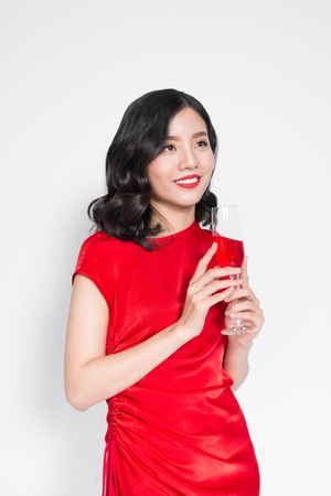 Young celebrating asian woman in red dress holding wine glass.の写真素材