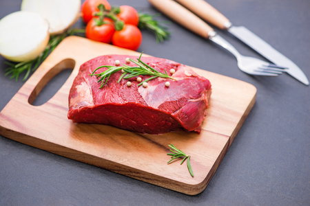 Raw beef on a cutting board  with spices and ingredients for cooking.の写真素材