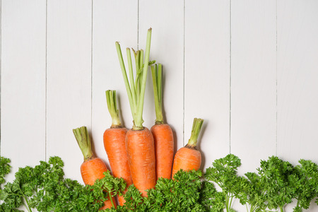 Fresh raw carrots with vegetables on wooden table.の写真素材