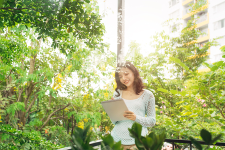 Young attractive sweet girl with notepad on a veranda. Spring mood.の写真素材