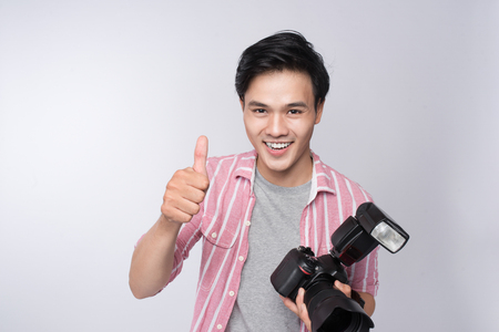 Young asian photographer holding digital camera, while working in studioの写真素材