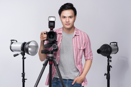 Young asian photographer holding digital camera, while working in studioの写真素材