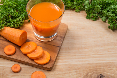 Glass of fresh carrot juice with vegetables on wooden table.の写真素材