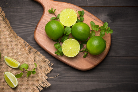 Fresh limes on cutting board on wooden table. Top view, background.の写真素材