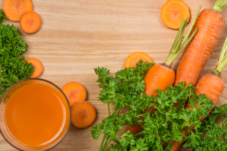 Glass of fresh carrot juice with vegetables on wooden table.の写真素材