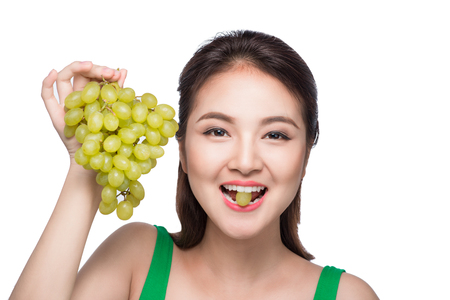 Young beautiful asian woman eating fresh grapes isolated on white backgroundの写真素材