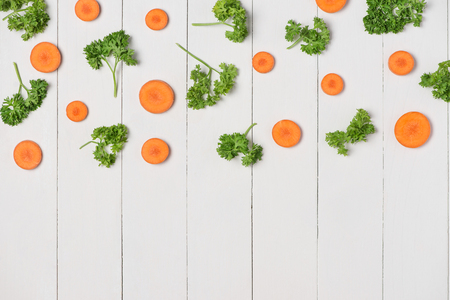 Fresh raw peeled carrot slices with vegetables on wooden table.の写真素材