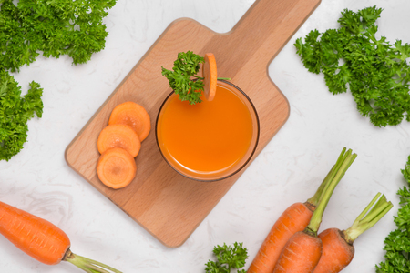 Glass of fresh carrot juice with vegetables on table.の写真素材