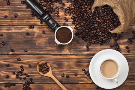 Coffee beans in spoon and cup of hot drinkの写真素材