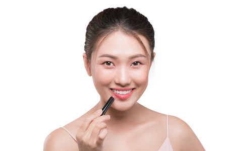 Beautiful young asian woman applying pink lipstickの写真素材