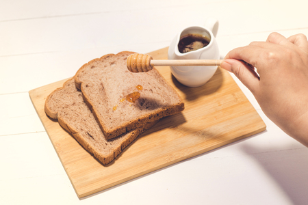 Close-up of slice of toast bread with honey on wood tableの写真素材