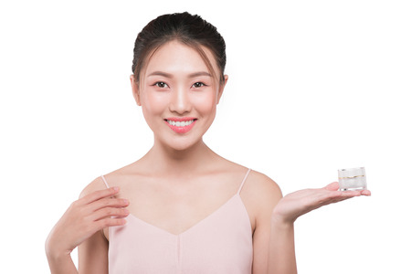 Attractive girl with soft skin and naked shoulders holding cream, a model with light nude make-upの写真素材