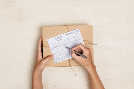 Top view of deliveryman making notes in return to vendor delivery receipt at table