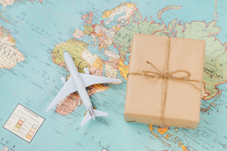 International shipping. White model airplane land on the geographical map backgroundの写真素材