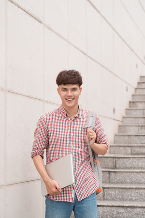 Student holding with laptop computer inside school campus buildingの写真素材