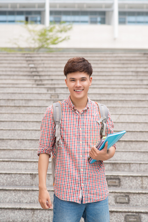 Smiling student with his books in universityの写真素材
