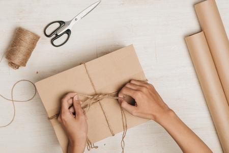 Man wrapping gift. A parcel wrapped in brown paper and tied with rough twineの写真素材