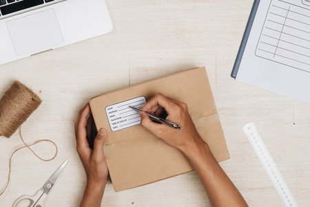 Top view of deliveryman making notes in delivery receipt at table