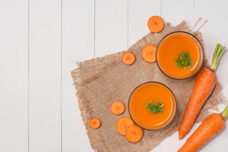 Fresh carrot juice in glass on wooden table.の写真素材