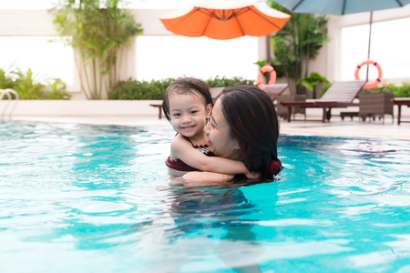 Mother and baby girl having fun in the pool. Summer holidays and vacation conceptの写真素材