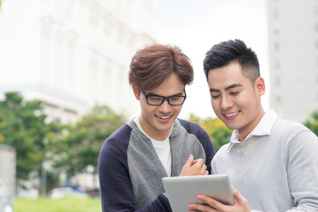 Smiling young businessman discussing surfing the Internet on the tabletの写真素材