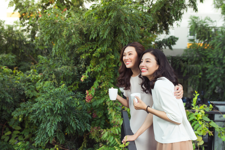 Happy young women friends well-dressed smiling while standing togetherの写真素材