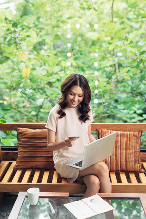 Beautiful asian womon holding a credit card and purchasing onlineの写真素材
