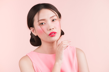 Beautiful asian girl with professional makeup and stylish hairstyle  isolated on pink. Cosmetics and make-upの写真素材