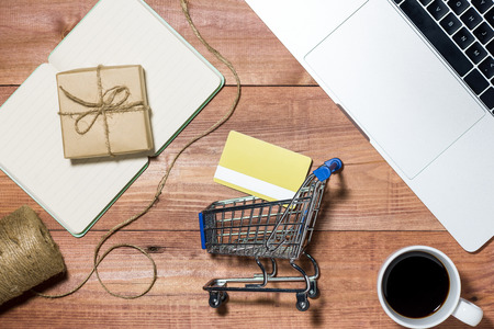 Shopping online concept. Small blue trolley and gadgets on the wooden table.の写真素材