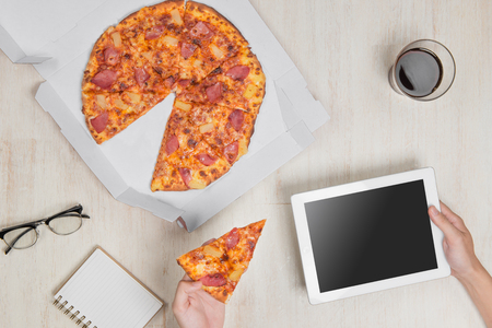 Top view image. Fast pizza delivery. Man eating and using a tabletの写真素材