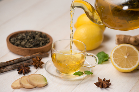 Cup of ginger tea with lemon and honey on white wooden background.の写真素材