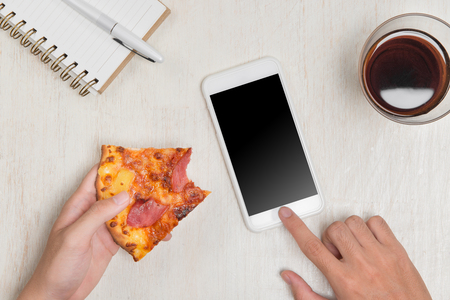 Hands ordering pizza with a device over a wooden workspace tableの写真素材