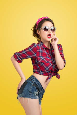 Sexy woman retro portrait  with pin-up make-up and hairstyle posing over yellow background.の写真素材
