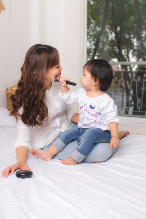 Lovely princess is applying the make up on her skin with special brush as she wants to look like her adult motherの写真素材