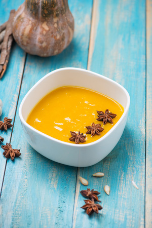 Pumpkin and carrot soup with cream and parsley on blue  wooden background.の写真素材
